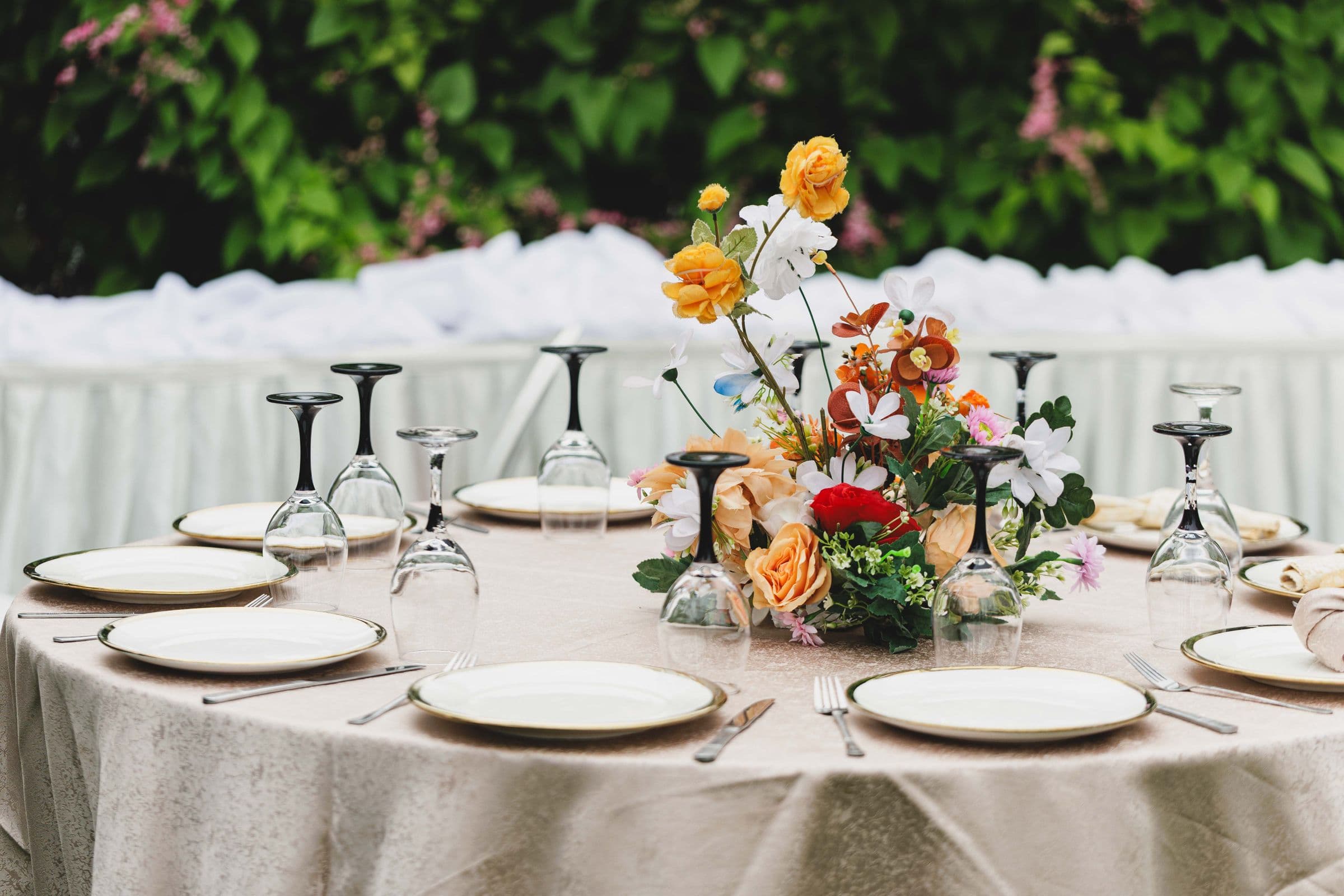 Festlich gedeckte Hochzeitstafel mit Blumengesteck im Freien